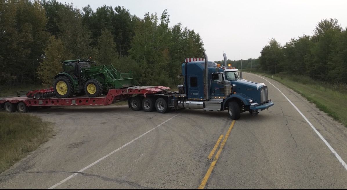 Lowbed transporting a tractor across Alberta