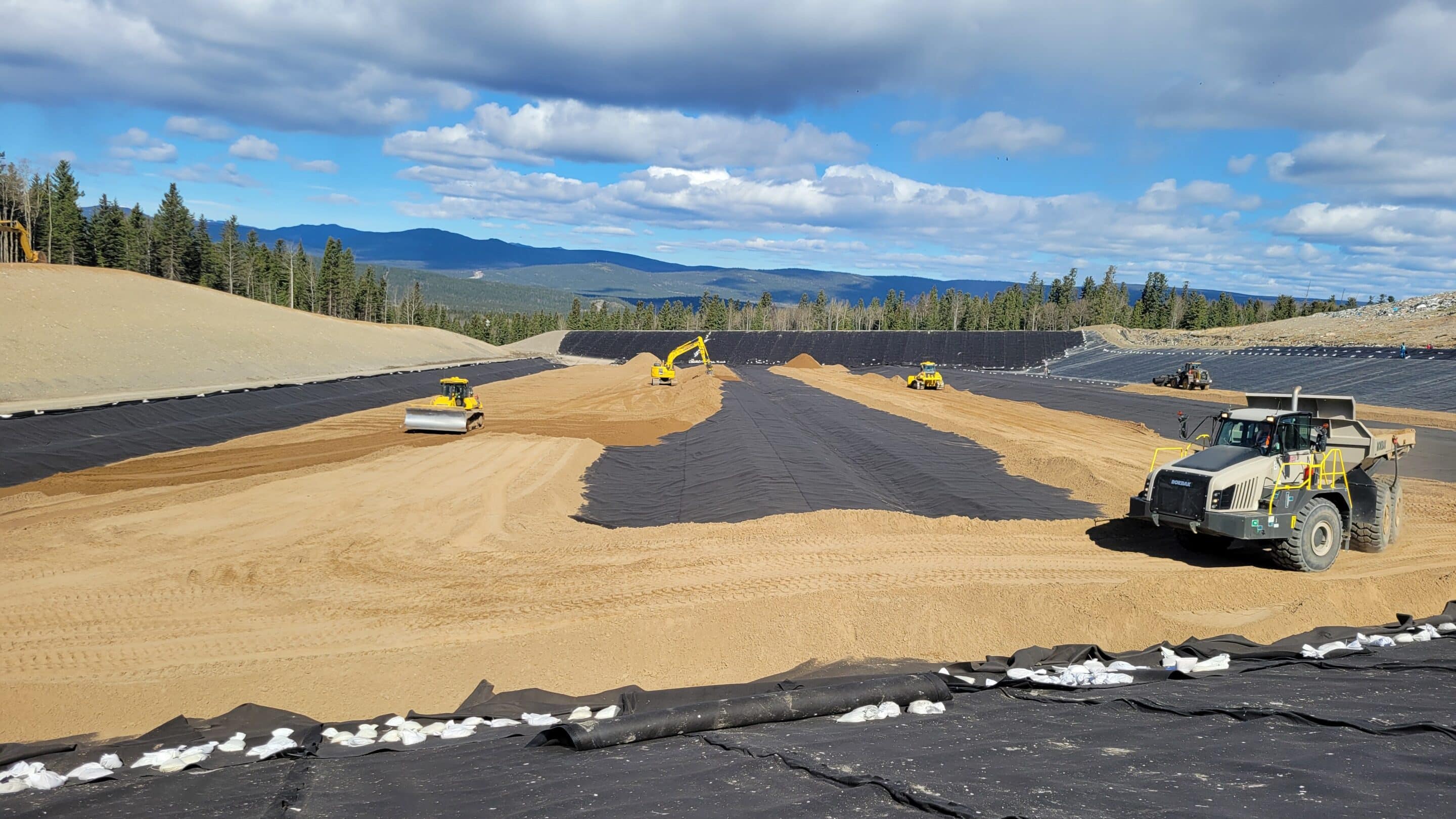 RTRC landfill cell construction with rock trucks, dozer, and excavators working in Alberta